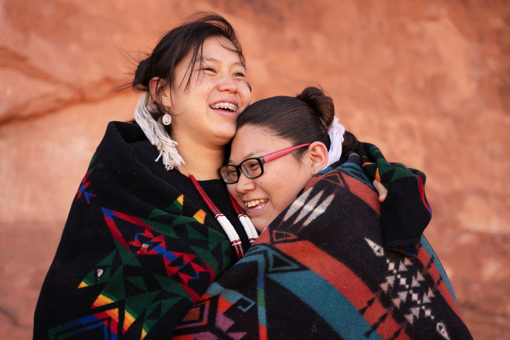 Two American Indian/Alaska Native women smiling while giving each other a hug.
