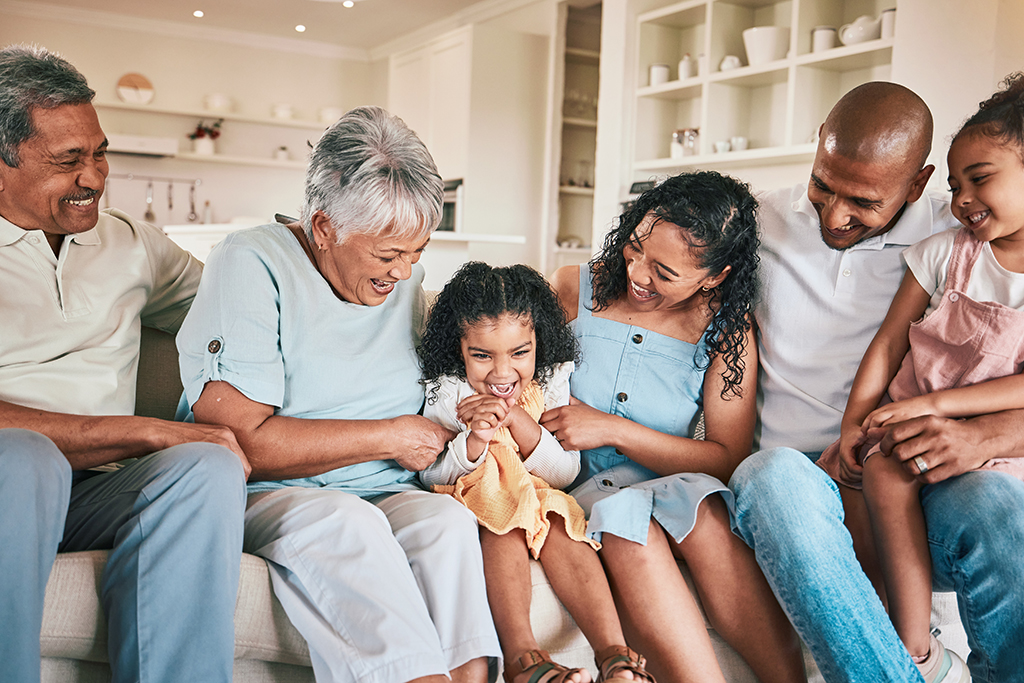 Happy multigenerational group sitting together on the couch, smiling.