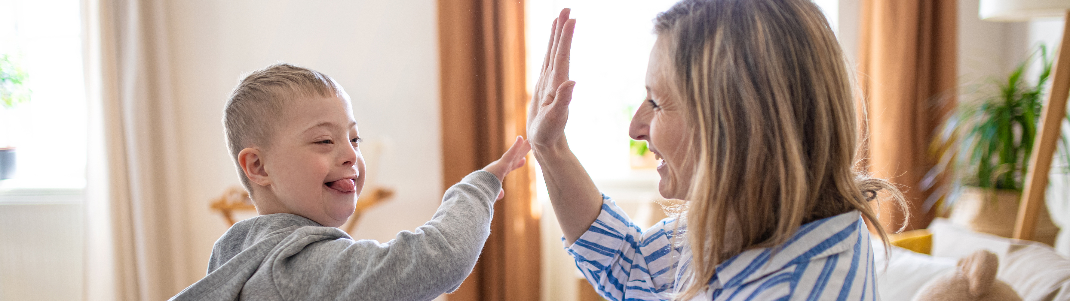 Woman and child with special needs high-fiving