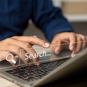 Man typing on laptop keyboard for online information search
