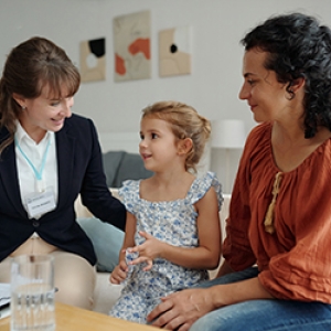 A mother and her young child in their living room sitting together as they work with a Case manager.