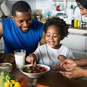 Young African American parents happily sharing a healthy meal with their young child.