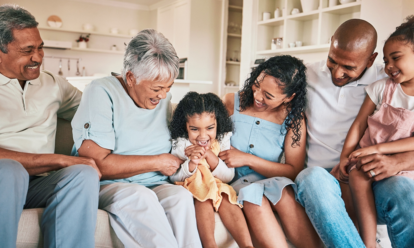 Happy multigenerational group sitting together on the couch, smiling.