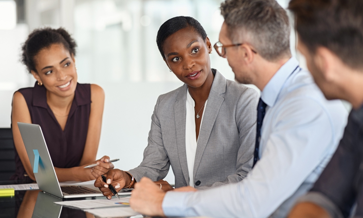 A diverse group of professionals sitting at a conference table having a conversation.