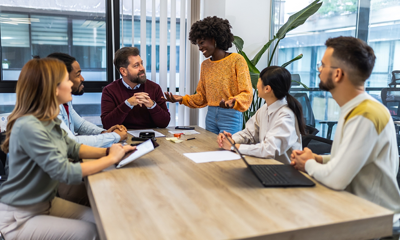 Diverse group of professionals engaging in a discussion around a conference table in a modern office.
