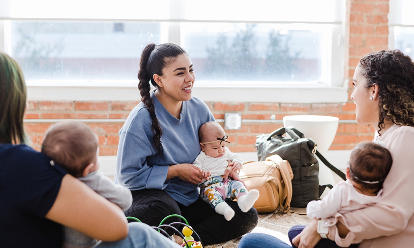 three adult women sitting in a circle each with a baby sitting in their laps 
