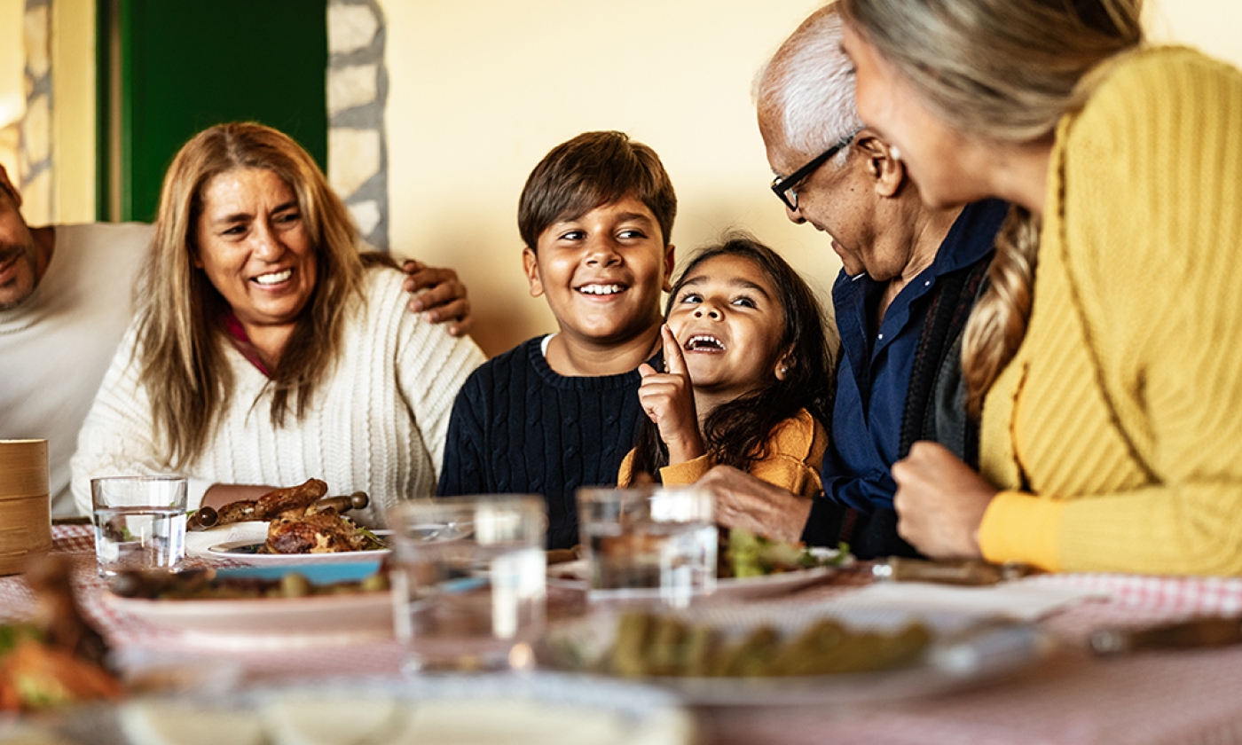 varying ages of diverse family members sitting at a dining table smiling