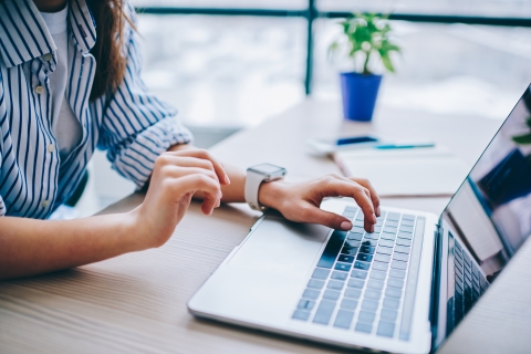 Cropped image of female hands searching web information via modern laptop computer
