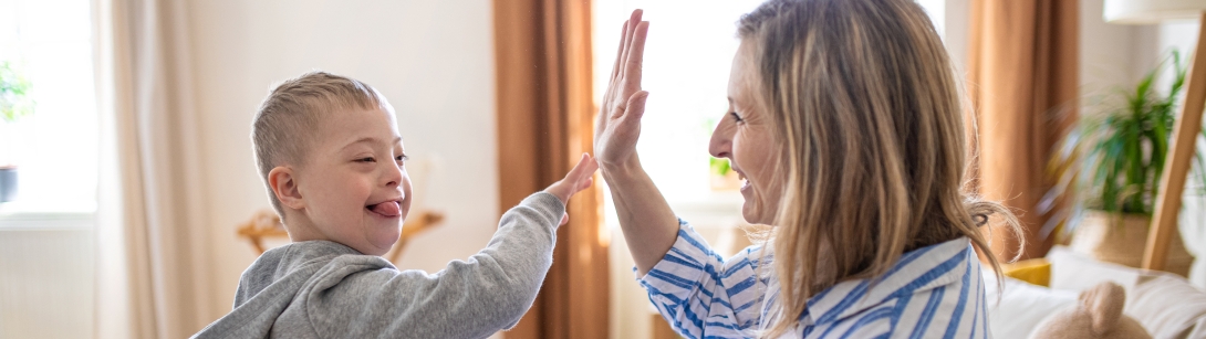 Woman and child with special needs high-fiving